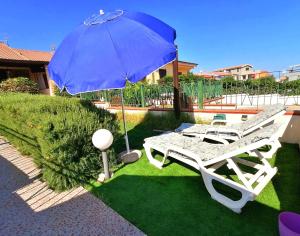 a blue umbrella and a chair and a table at Sardamare Apartments Appartamenti La Ciaccia in Valledoria