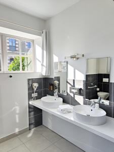 une salle de bains blanche avec deux lavabos et une fenêtre dans l'établissement Hotel Château de la Barbinière, à Saint-Laurent-sur-Sèvre