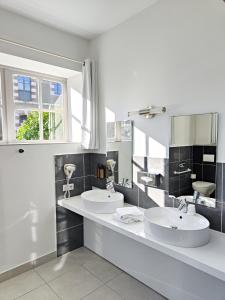 Baño blanco con 2 lavabos y ventana en Hotel Château de la Barbinière en Saint-Laurent-sur-Sèvre