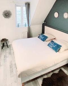 a bedroom with a white bed with blue pillows at Cosy appartement dans une villa avec piscine, proche du centre et de la mer in Cabourg