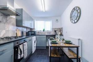 een keuken met een tafel en een klok aan de muur bij Stunning 3-Bedroom House Sleeps 8 in Liverpool