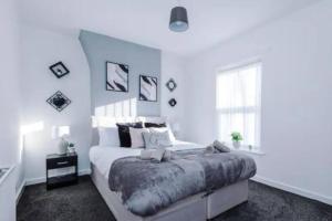 een witte slaapkamer met een groot bed en een raam bij Stunning 3-Bedroom House Sleeps 8 in Liverpool