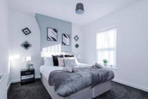 a white bedroom with a large bed and a window at Stunning 3-Bedroom House Sleeps 8 in Liverpool