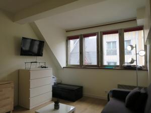 sala de estar con TV y algunas ventanas en Les jardins du gros Horloge, studio en Ruan