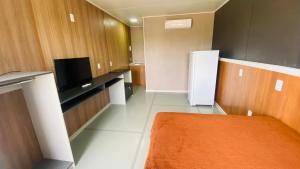 a room with a refrigerator and a tv in it at Kitinete Mobiliada in Chapecó