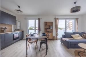 a living room with a table and a couch at L'Edulis - A 100m de la plage et parking privé in Courseulles-sur-Mer