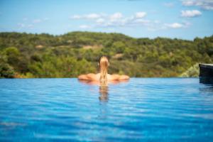 une personne assise dans l'eau dans une piscine dans l'établissement Château de Villarlong, à Villarzel-Cabardès