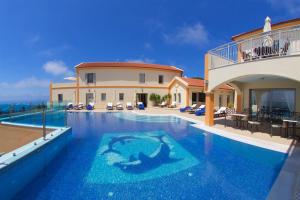 a villa with a swimming pool in front of a building at Belle View Hotel - Sea View & Sunset in Mánganos