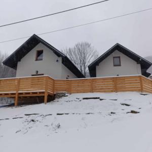 a house with a wooden fence in the snow at Domki Nad Potokiem in Rytro