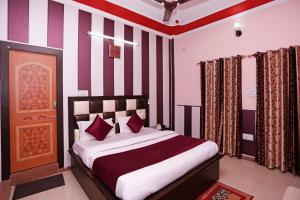 a bedroom with a bed with red and white stripes at Mehfil Hotel in Jawālāpur