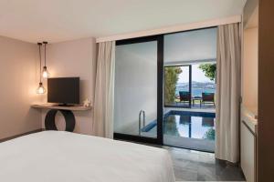 a bedroom with a bed and a view of a pool at Le Meridien Bodrum Beach Resort in Bogazici +185 photos