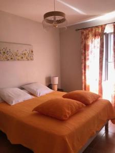 a bedroom with a large bed with orange sheets and pillows at Gîte/Appartement Saint Bernard in Le Thoronet