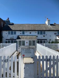 una cerca blanca frente a una casa blanca en Beautiful Beach Front Cottage en Llandudno