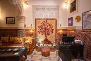 una sala de estar con sofá y un árbol en la pared en Riad Le Petit Patrimoine De Fés en Fez