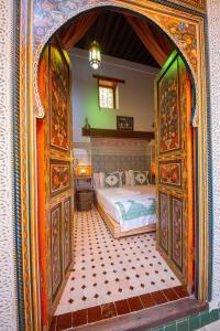 1 dormitorio con 1 cama en una habitación con puerta abierta en Riad Le Petit Patrimoine De Fés, en Fez