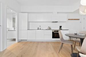 cocina con armarios blancos, mesa y sillas en Seaside apartment with magical balcony view en Aarhus