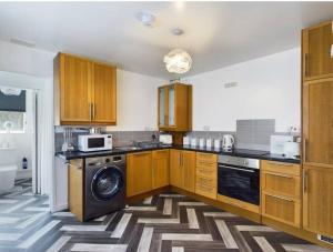 een keuken met houten kasten en een vaatwasser bij Work & Relax - 2 bedroom house with off-road parking in Swansea