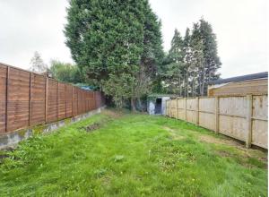 a fence in a yard with a grass field at Work & Relax - 2 bedroom house with off-road parking in Swansea