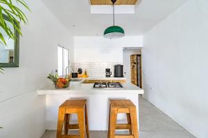 a kitchen with a white counter and wooden stools at Casa Bonimus in Santa Teresa Beach