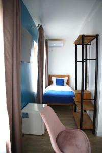 um pequeno quarto com uma cama e uma cadeira em English House em Bistriţa