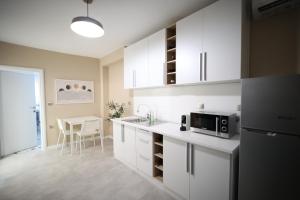 a kitchen with white cabinets and a refrigerator and a table at Ε121 Luxury Suites in Edessa