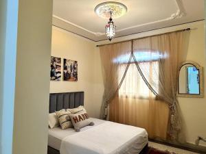 a bedroom with a bed with a window and a chandelier at Spacious fantastic closeby airport and city in Marrakesh