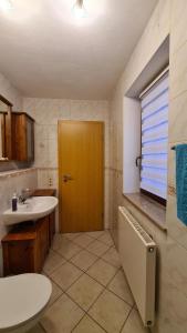 een badkamer met een wastafel en een houten deur bij Ferienwohnung Lippmann in Dorfchemnitz