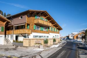 un grand bâtiment en bois sur le côté d'une rue dans l'établissement Bijou Lohnerblick - sonnig mit Terrasse&Bergsicht, à Adelboden