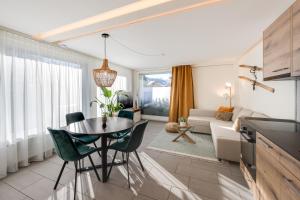 - un salon avec une table, des chaises et un canapé dans l'établissement Bijou Lohnerblick - sonnig mit Terrasse&Bergsicht, à Adelboden