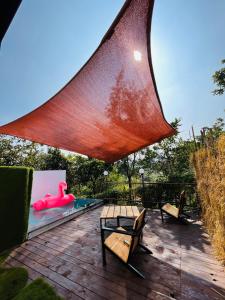 a patio with two benches and a swimming pool with a large sail at THE CANVAS LONAVLA in Lonavala