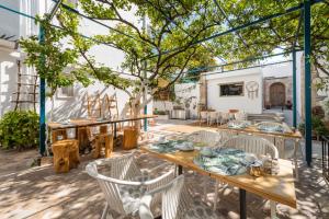 um pátio com mesas, cadeiras e uma árvore em Lefka Hotel & Apartments in Ilha de Rhodes