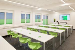 uma sala de aula com mesas brancas e cadeiras verdes em Good Rooms GmbH Guntramsdorf em Guntramsdorf
