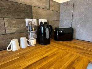 a coffee maker and coffee cups on a wooden floor at Tractor and Lawnmower Apartments in Boston