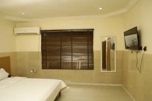 1 dormitorio con 1 cama y ventana con TV en CALBERT LODGE en Abuja