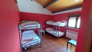 a room with two bunk beds in a red room at Albergue Villa de Salvatierra in Salvatierra de Tormes