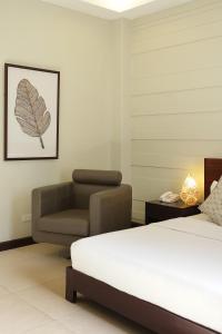 a bedroom with a bed and a chair at Alba Uno Hotel in Cebu City