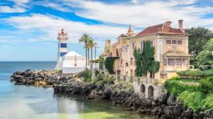 a house and a lighthouse next to the ocean at Dream In Cascais - Checkinhome in Cascais