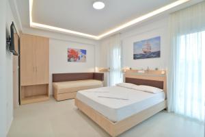 a white bedroom with a bed and a window at Evas Rooms in Nei Poroi