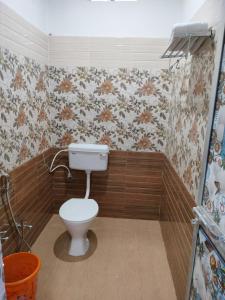 baño con aseo y papel pintado con motivos florales en Hotel Infinity, en Rajgir