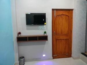Habitación con TV de pantalla plana y puerta de madera. en Hotel Infinity, en Rajgir