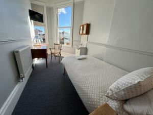 Schlafzimmer mit einem Bett, einem Schreibtisch und einem Tisch in der Unterkunft The Elms Guest House Bristol in Bristol