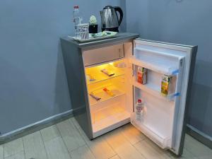 un frigorifero vuoto con la porta aperta in una cucina di Imhotep pyramids INN a Il Cairo