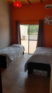 a bedroom with two beds and a door to a patio at Quinta barrio cerrado pileta tranquilidad naturaleza in Francisco Álvarez