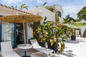 CapoBlu Hotel في بولا: فناء فيه كراسي ومظلة ونباتات