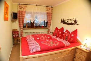 Schlafzimmer mit einem Bett mit roten und weißen Kissen in der Unterkunft Alpenspatzl in Reit im Winkl