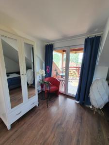 d'un salon avec une chaise rouge et une porte coulissante en verre. dans l'établissement Sunshine Apartment Velence, à Velence