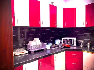 a kitchen counter with red cabinets and a microwave at Homestay-a better living in Lucknow