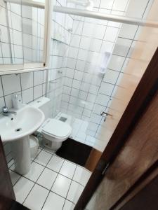 a white bathroom with a toilet and a sink at Queen's Flats in Brasília