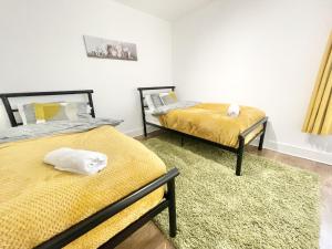2 letti in una camera con lenzuola gialle di MUST VIEW - Slick Retreat in Holloway - Next to Emirates Stadium - Sleeps up to 6 a Londra