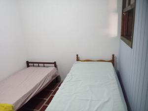 2 camas en una habitación con paredes blancas en Aluguel da Léo, en Cidreira